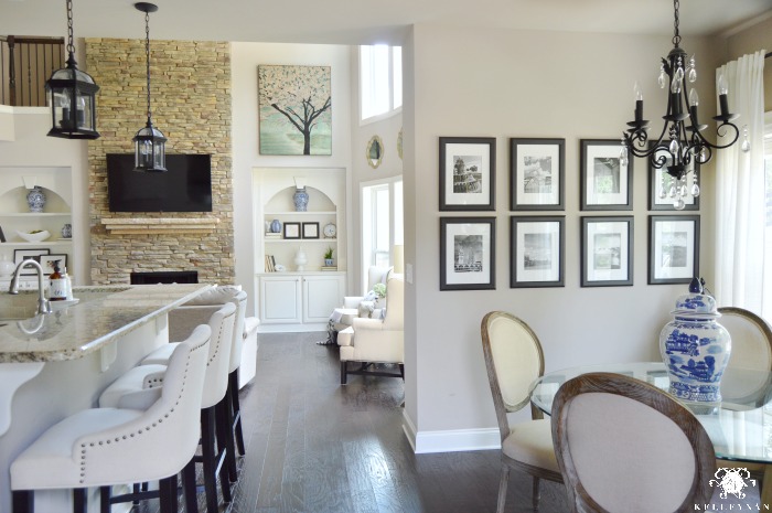 Two Story Great Room Open Concept Home with Tall Stacked Stone Fireplace Black and White Gallery Wall and Two Story Windows