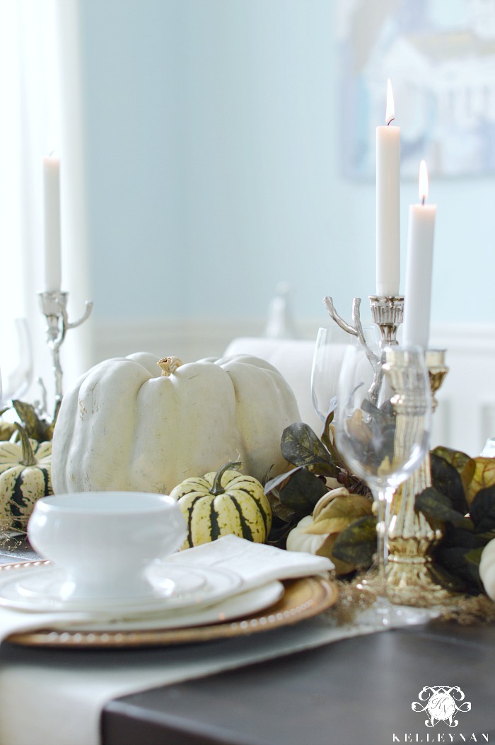 pumpkin-centerpiece-on-fall-table-with-white-and-greed-gourds-and-silver-candle-holders
