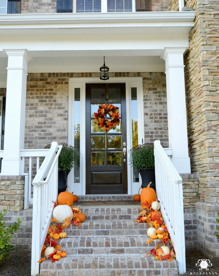traditional-fall-front-porch-on-brick-and-stone-home-with-pumpkins-and-leaves-cascading-down-stairs