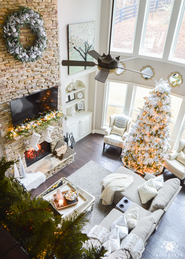 two-story-christmas-great-room-with-stacked-stone-fireplace-neutral-decor-with-silver-white-and-gold-tv-above-fireplace