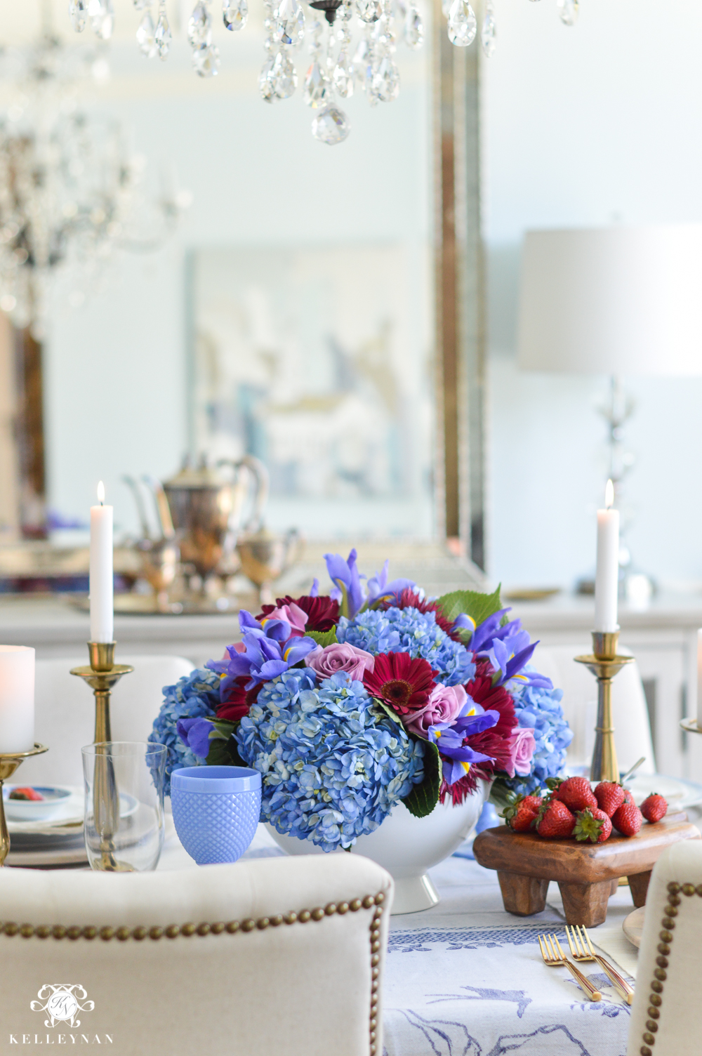 Blue, purple, and pink floral arrangement with strawberries on wooden paddle board