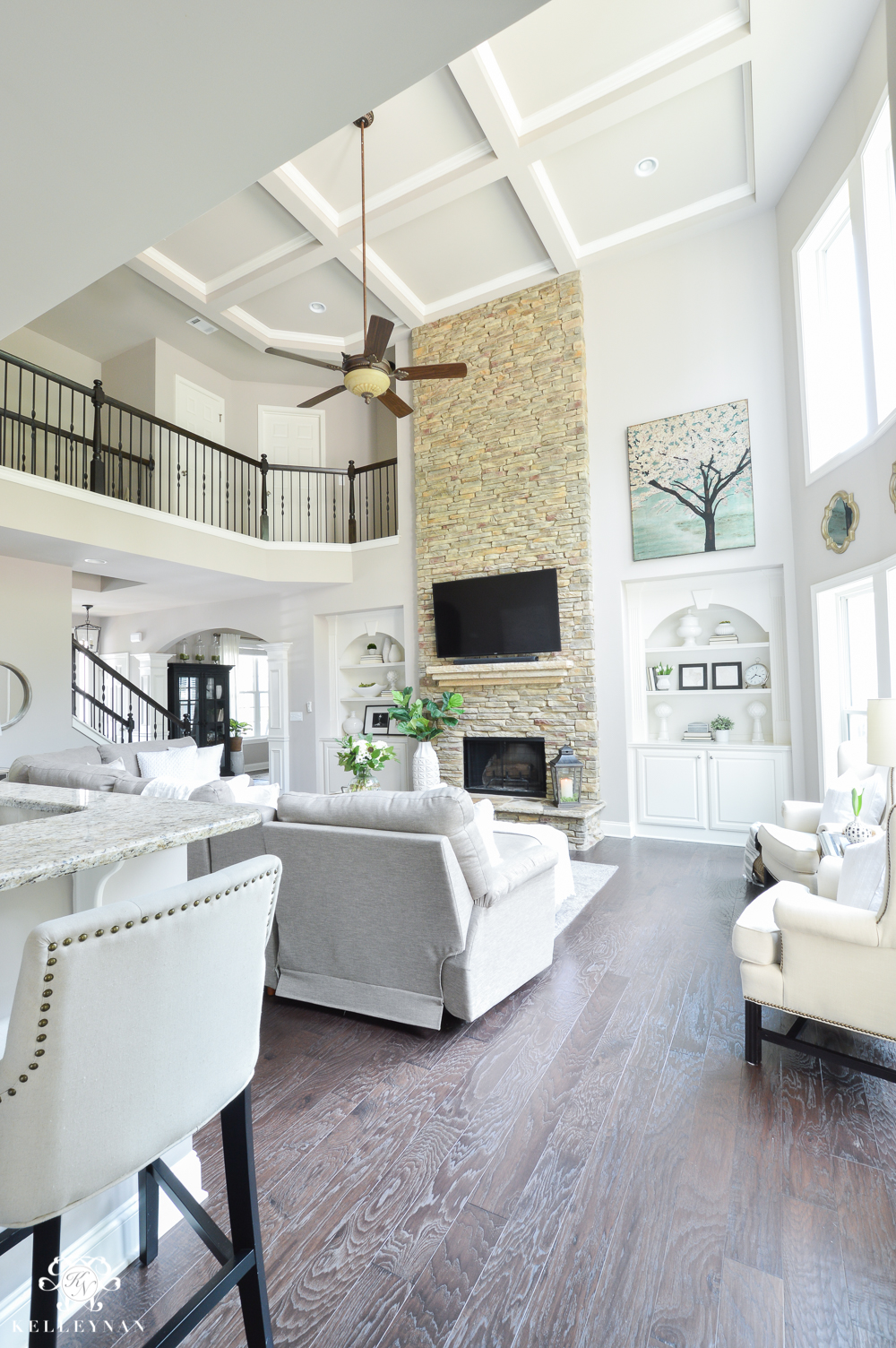 Shades of Summer Home Tour with Neutrals and Naturals- Two story living room with coffered ceiling and stacked stone fireplace with builtins