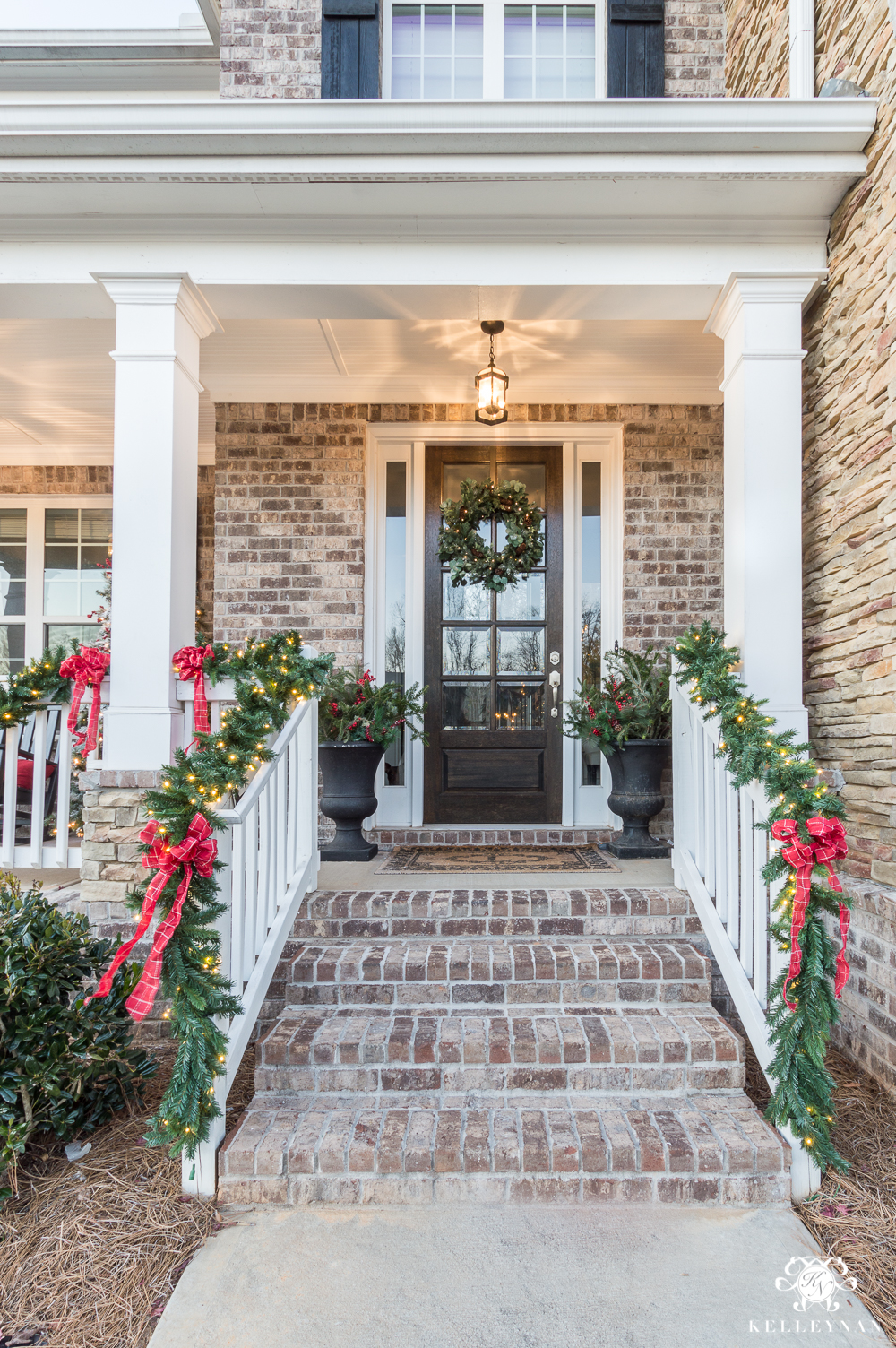 Classic Christmas front porch with green garland and red bows