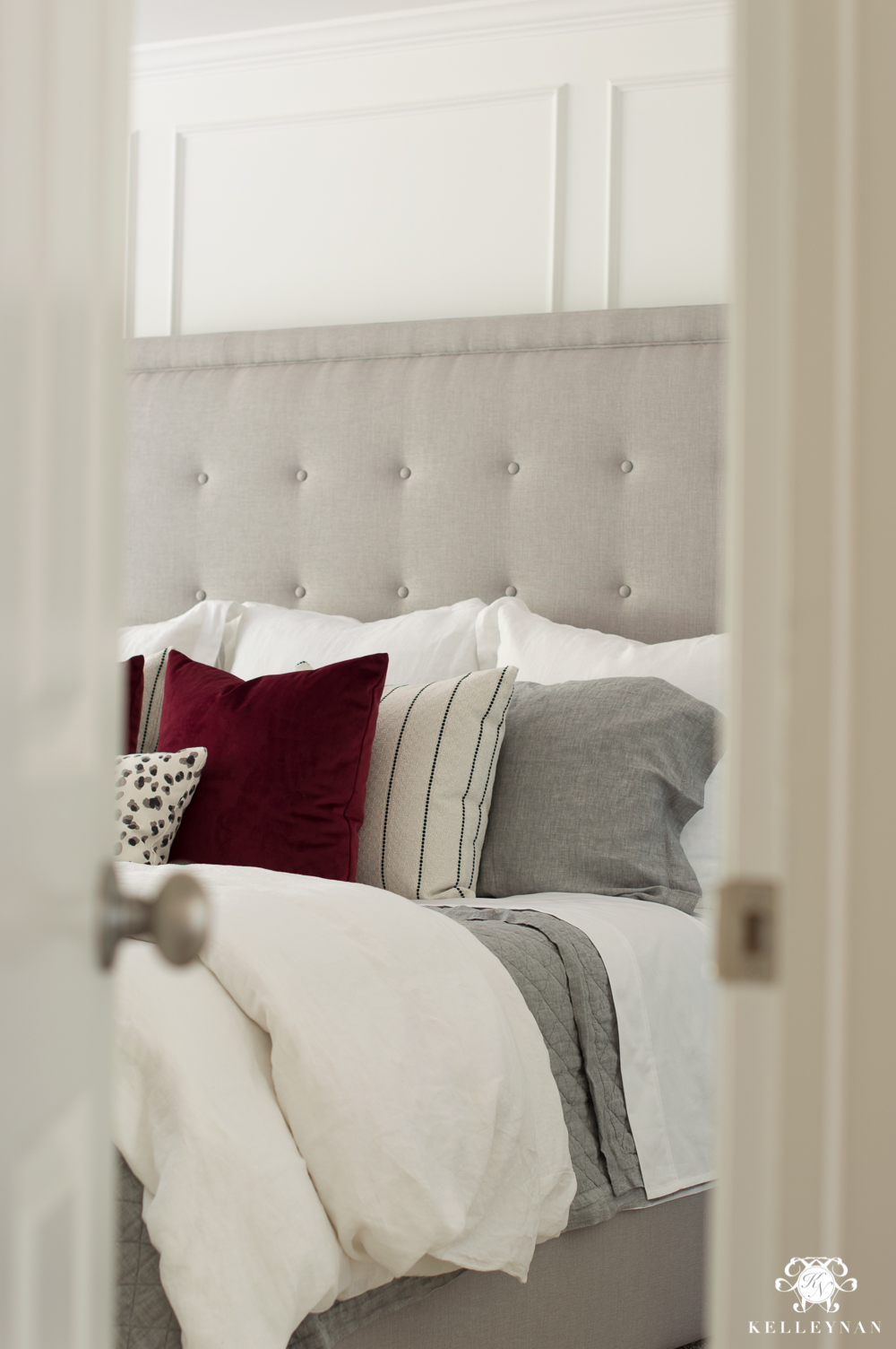 Master bedroom reveal sneak peek with gray tufted headboard and red pillows