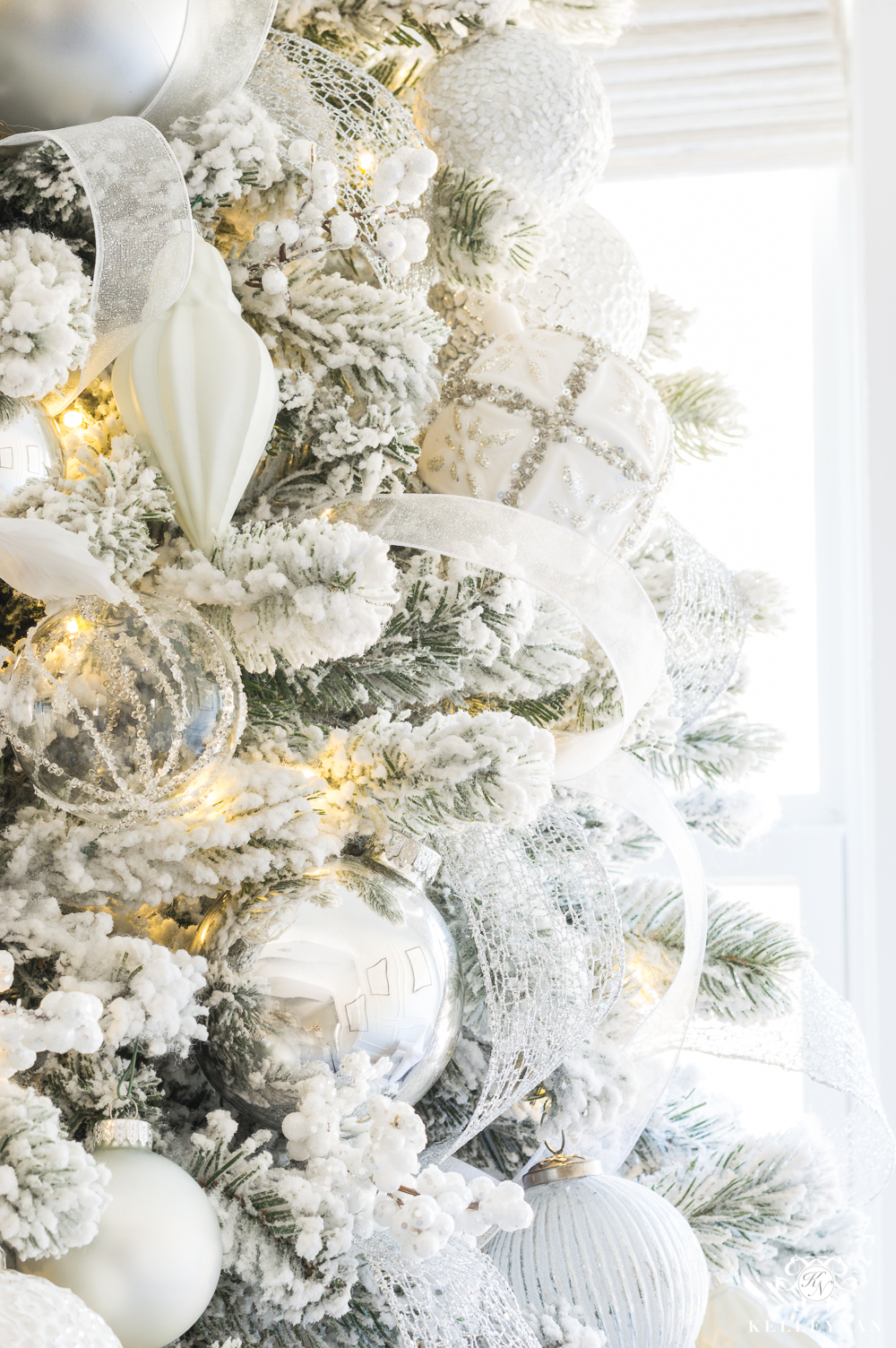 White and silver balsam hill christmas tree ornaments on flocked tree