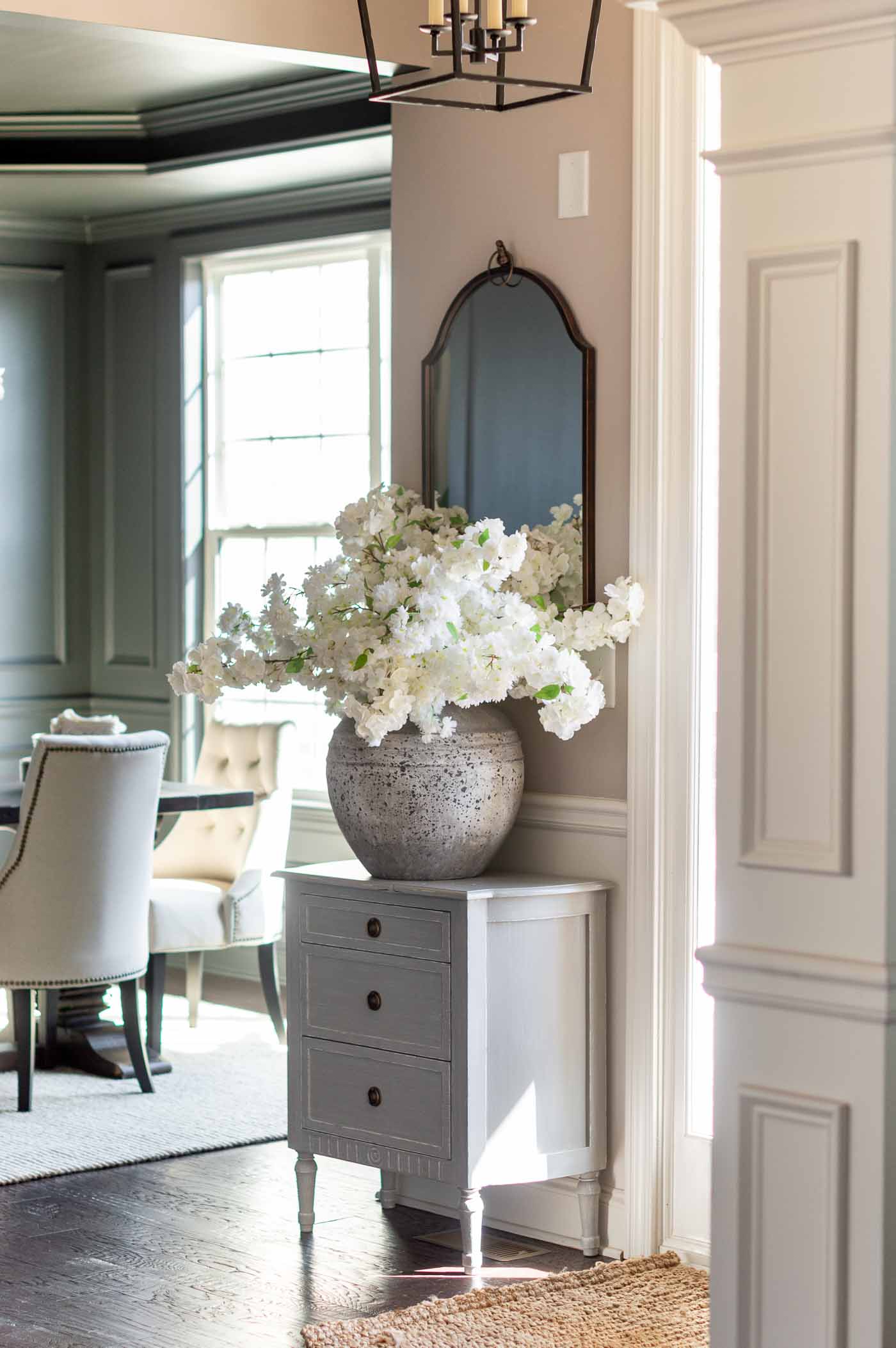 Entryway in Sherwin Williams Versatile Gray Paint -- a Warm Greige Interior Paint Color with Sherwin Williams Iron Ore Charcoal Paint in the Dining Room Background