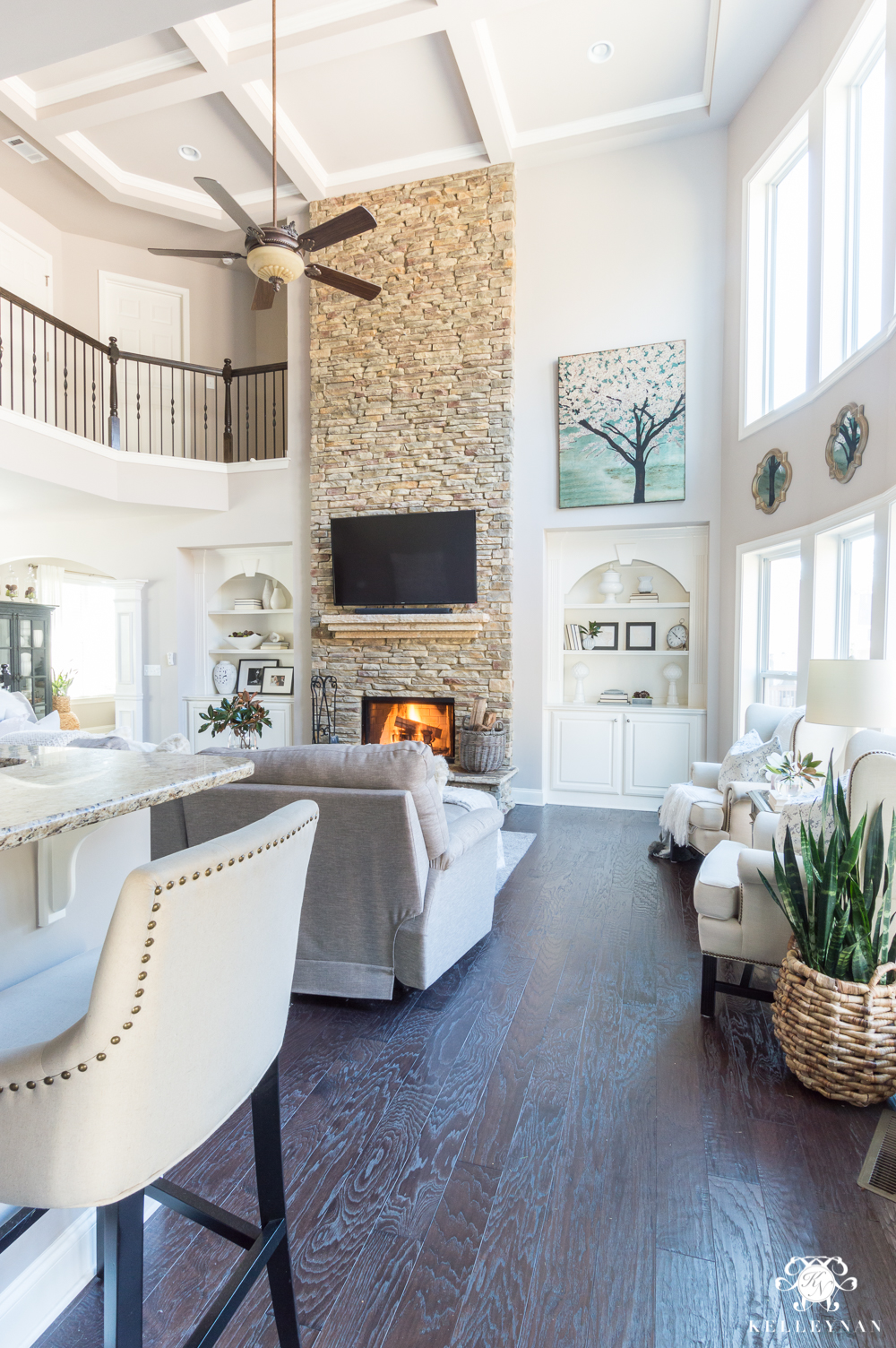 Two story living room with big stone fireplace and Versatile Gray painted walls