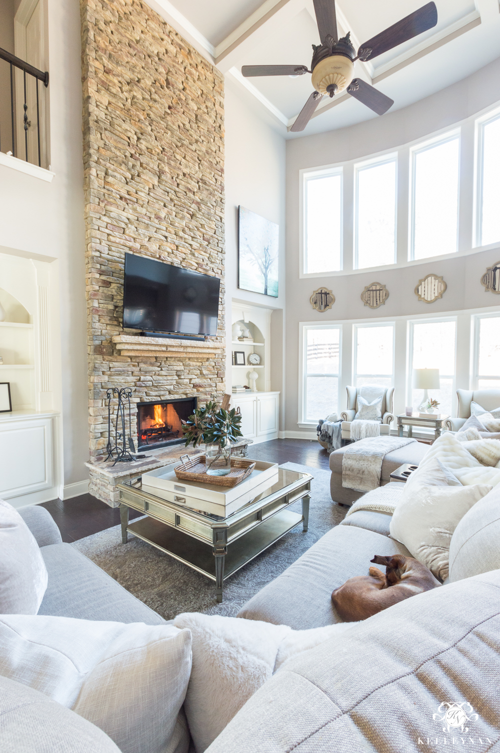 Stacked stone living room fireplace with two story row of windows