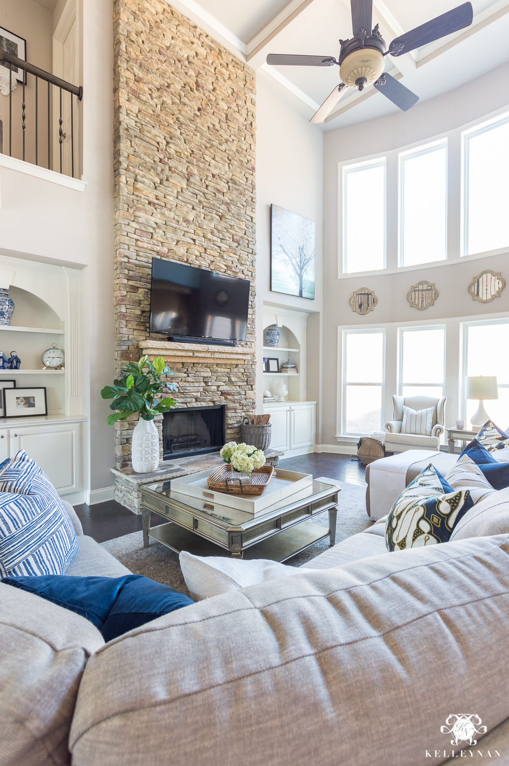 Versatile Gray Living Room with Stacked Stone Tall Fireplace