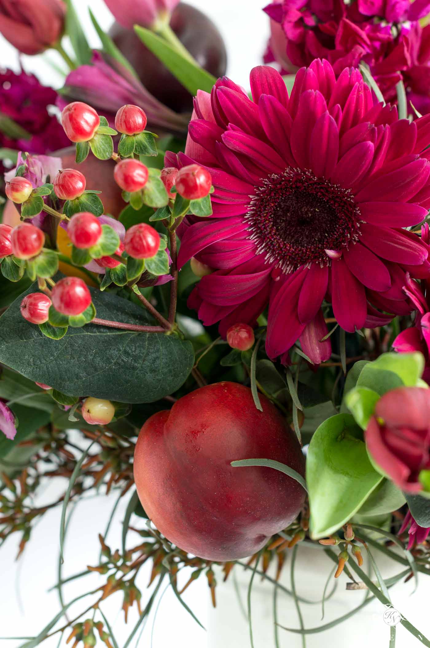 Pink, Purple, and Red Flowers with Nectarines and Plum fruit in a centerpiece arrangement 