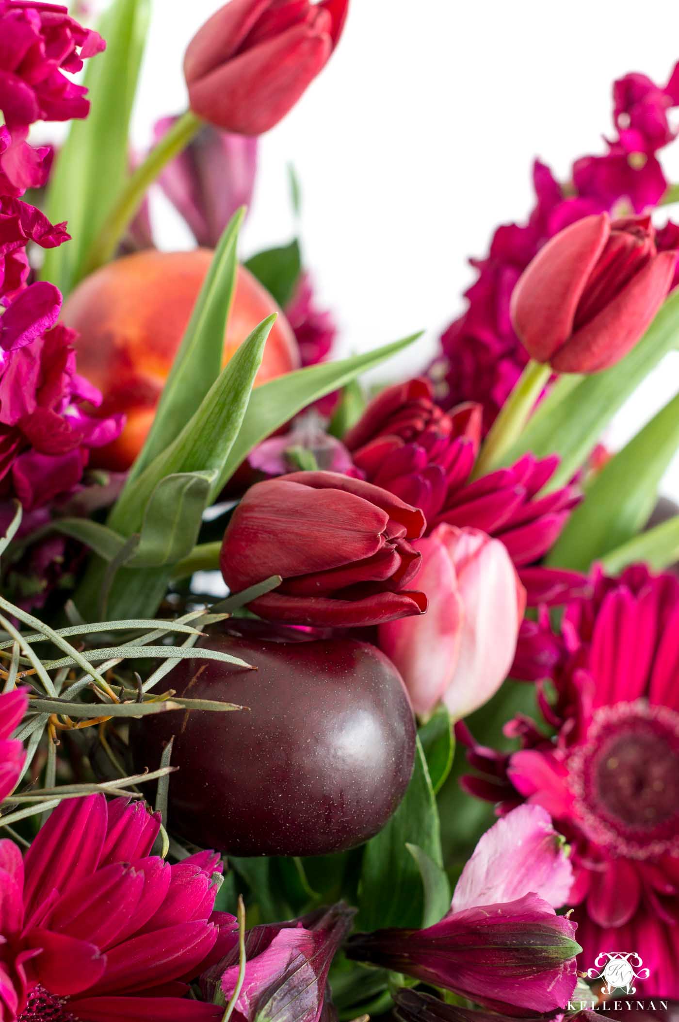 Fruit and flower combinations to create a stunning centerpiece with pink, purple, and red flowers and plums