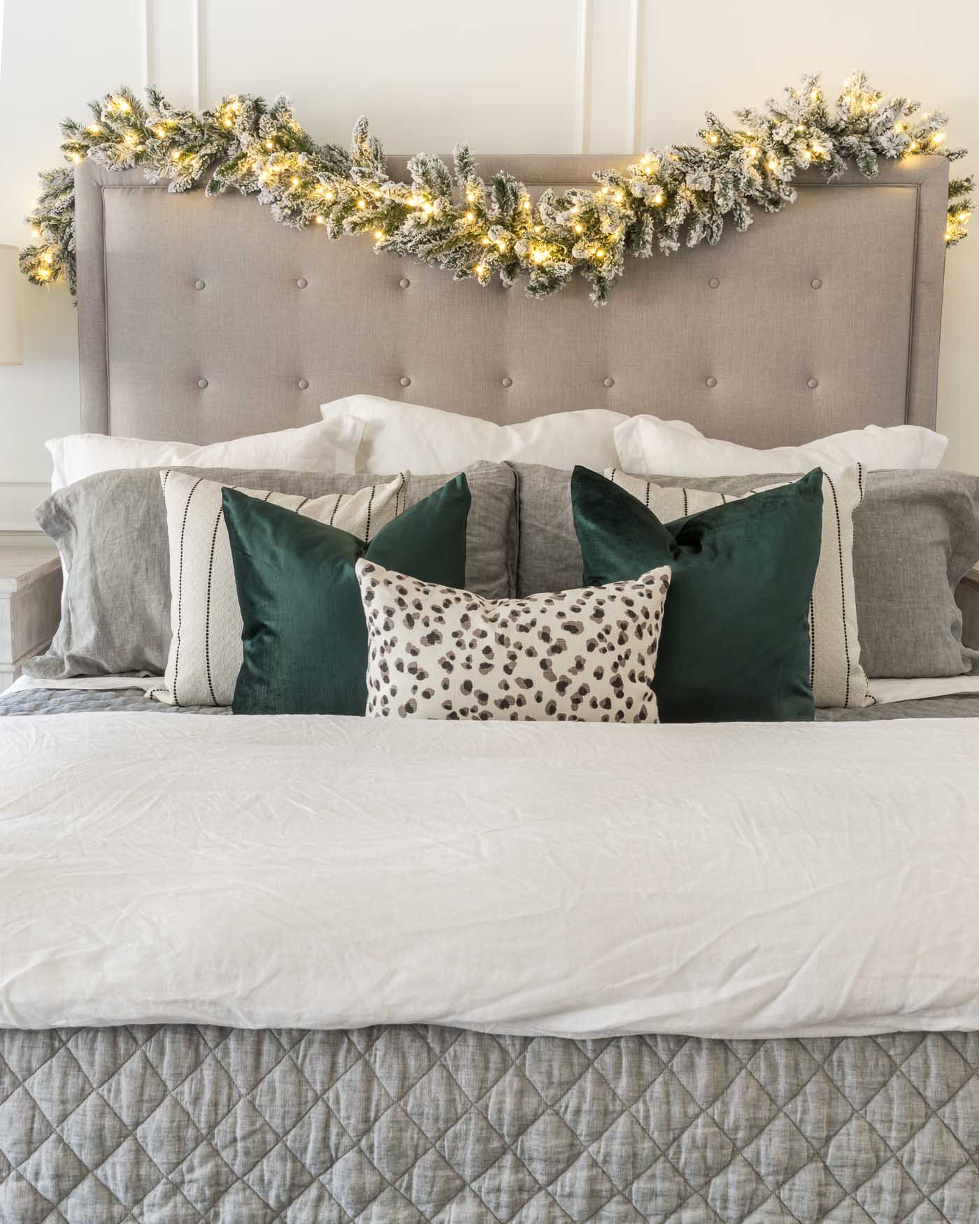 Christmas Decor Ideas for the Bedroom- Garland and Lights Draped Over Tufted Headboard