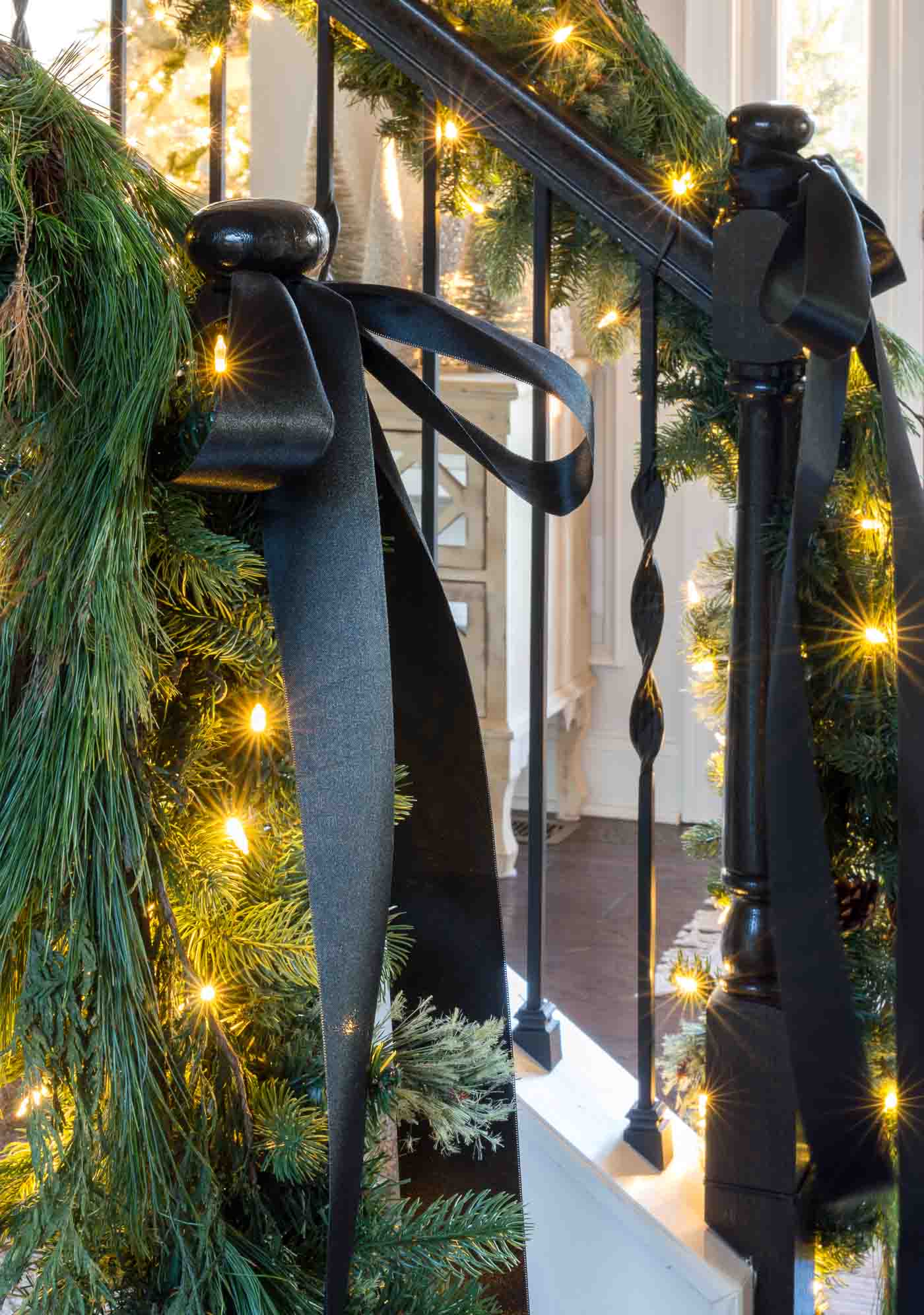 How to decorate a stair banister with greenery and Christmas garland with black satin ribbon