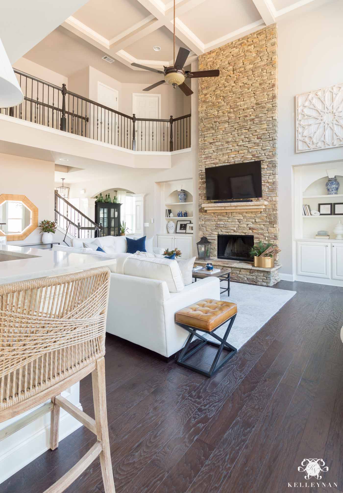 Classic, pretty living room with white sofas and tall stacked stone fireplace