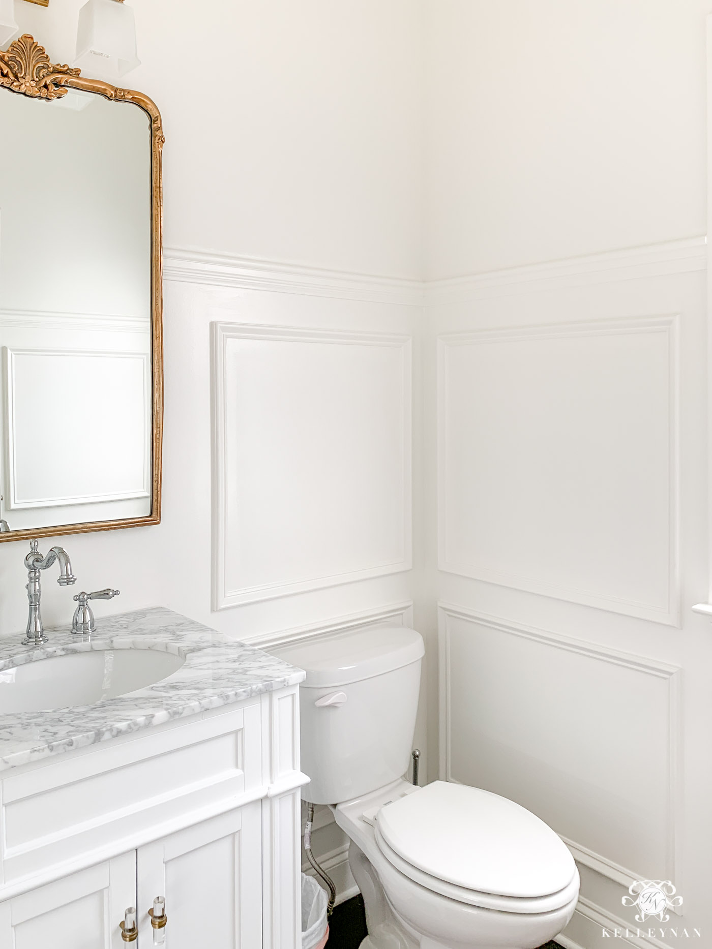 Powder room makeover progress with vintage brass mirror and wall molding