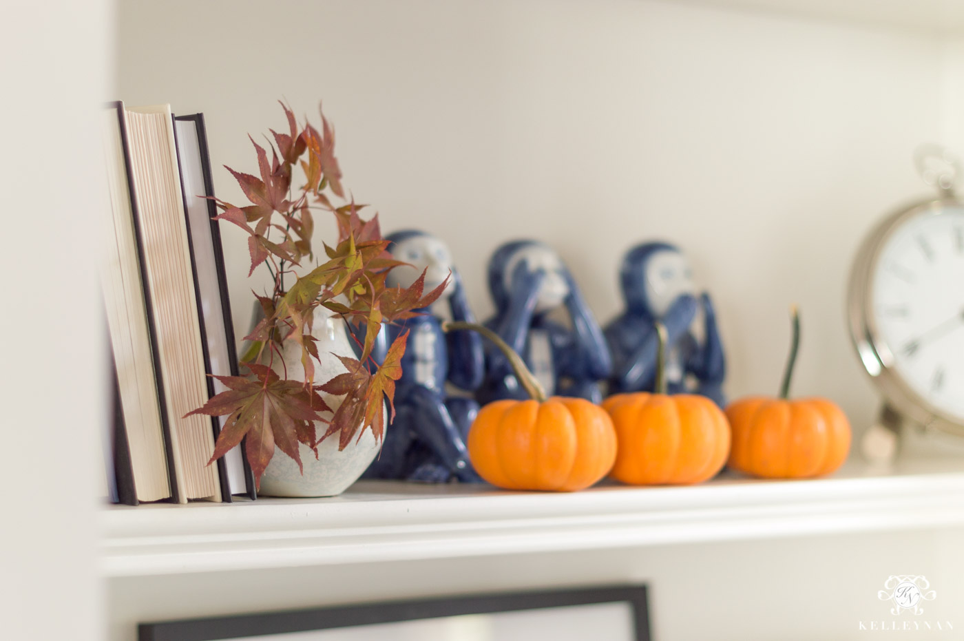 Fall shelf decor in the living room with orange pumpkins and maple leaves